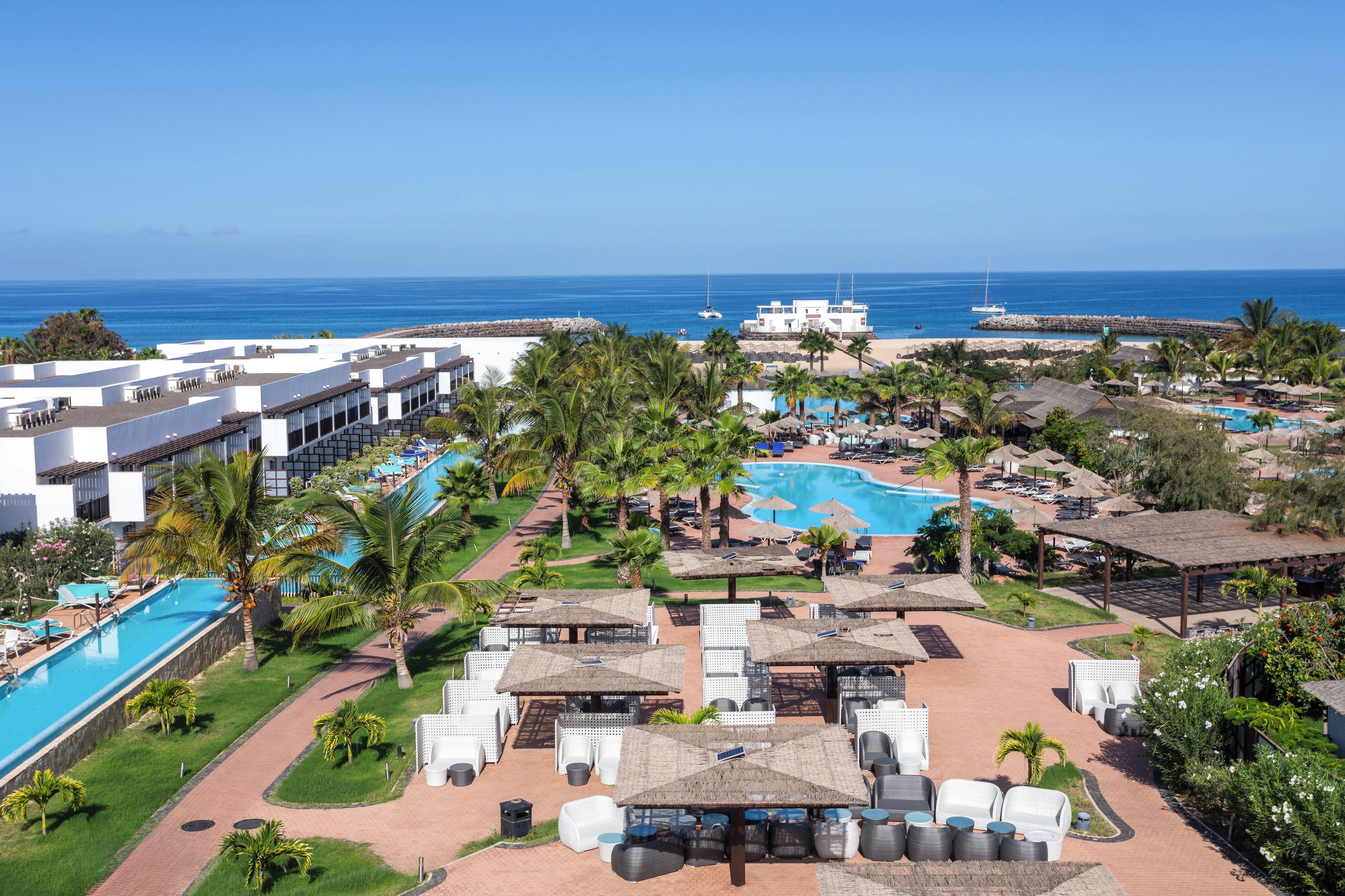 Een resort met een groot zwembad, een strandgedeelte en uitzicht op de oceaan.