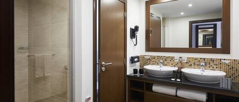 Une salle de bain avec deux lavabos, une douche et un grand miroir.