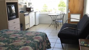 A compact room with a bed, a kitchenette, a dining table, and a chair. - Isle of Capri Motel (North Wildwood)