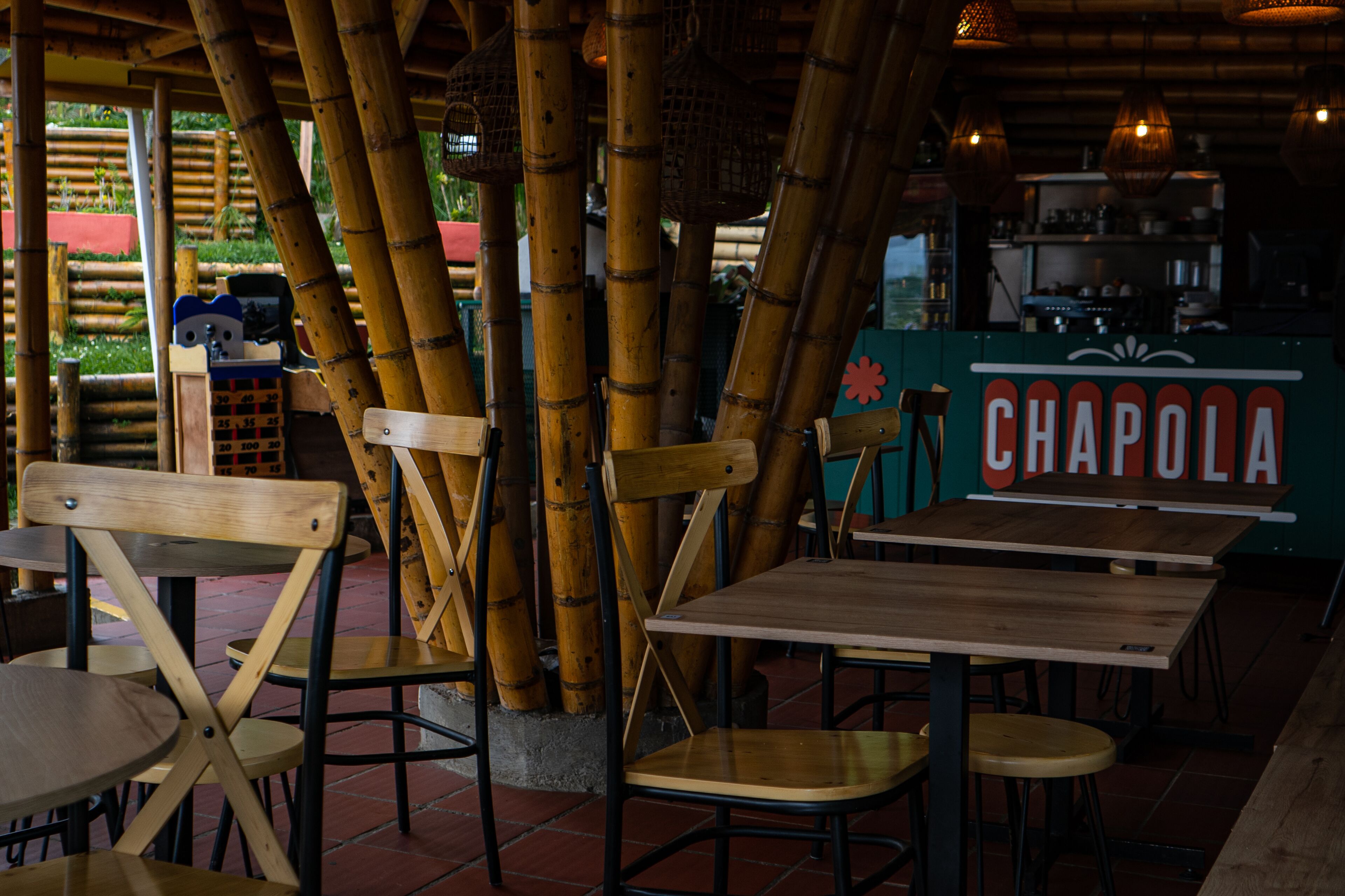 A restaurant interior with bamboo pillars, wooden tables, and chairs.