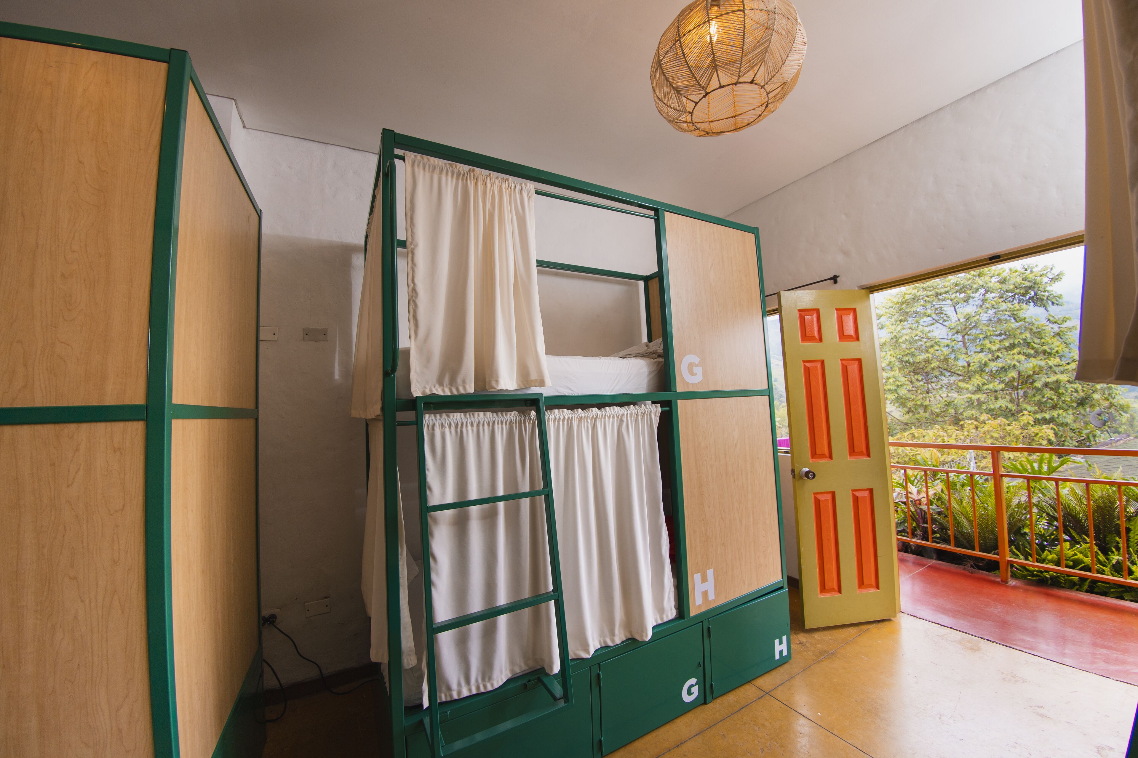 A bunk bed with storage drawers, a door with a letter 'G' on it, and a balcony with a railing.