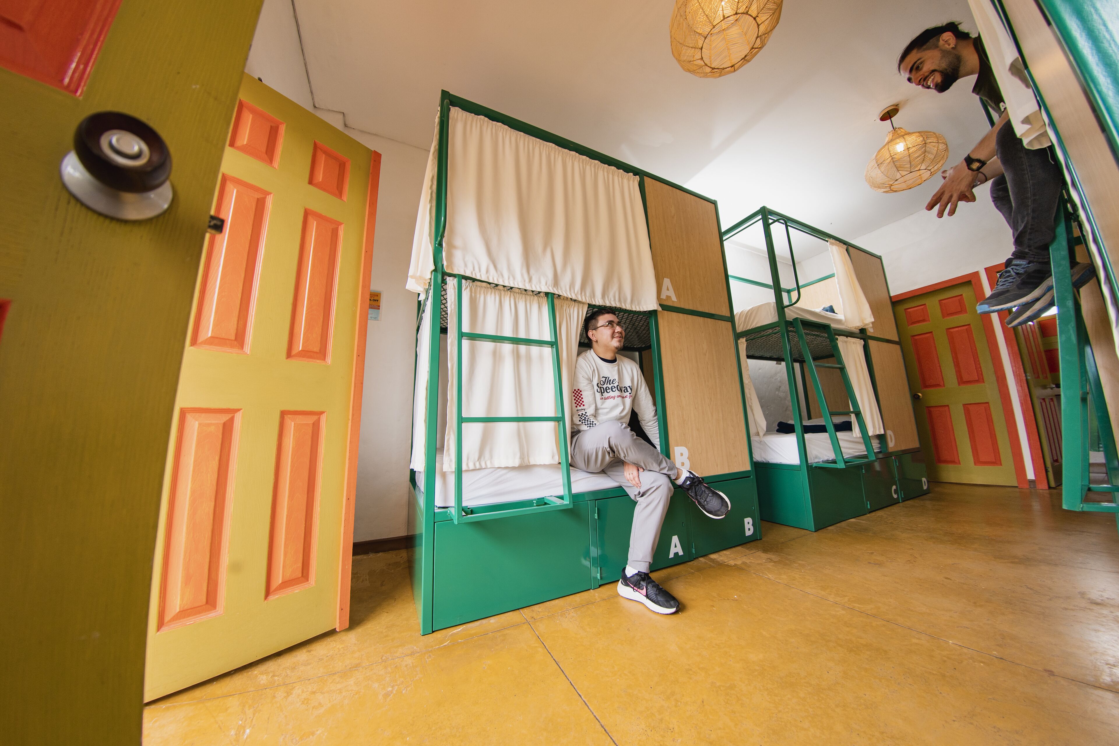 A room with bunk beds, green and orange walls, and a yellow floor.