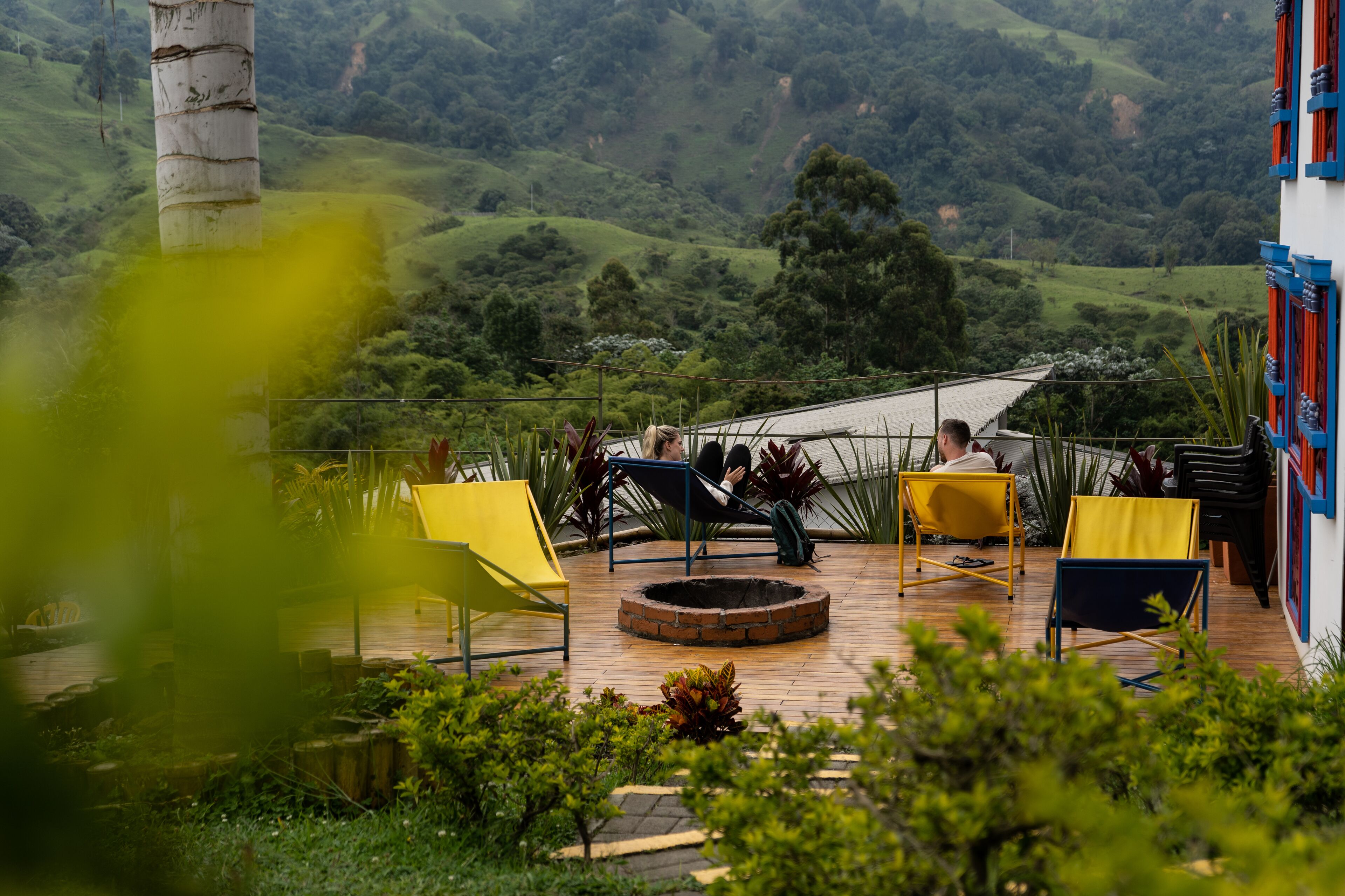 A terrace with outdoor seating, a brick fire pit, and a view of a green valley.