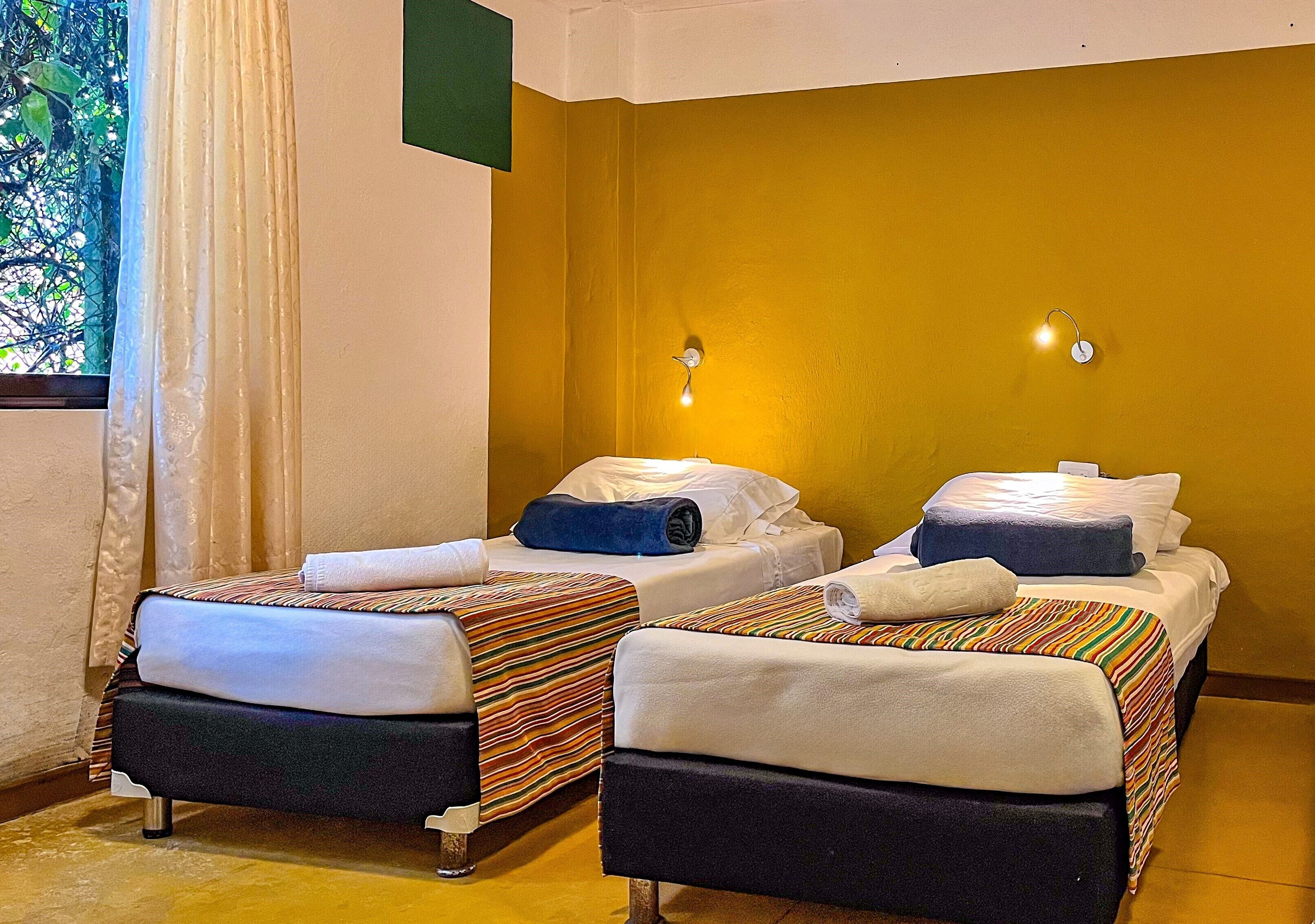 Une chambre d’hôtel avec deux lits, chacun étant équipé de draps à rayures et d’une serviette enroulée.