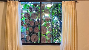 Una habitación con cama, una mesita de noche de madera y una ventana con cortinas.