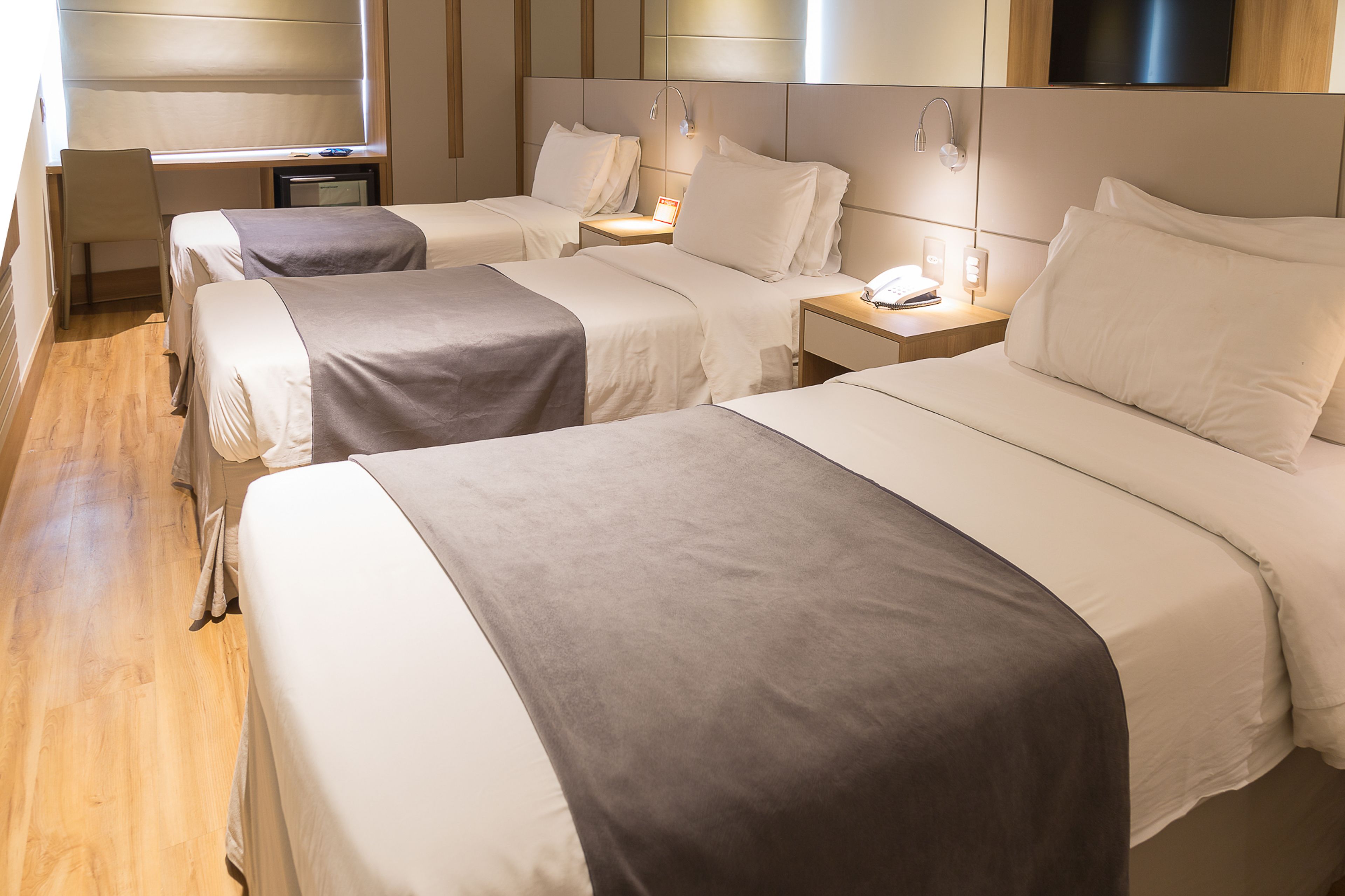 A hotel room with two beds, a desk, and a TV.