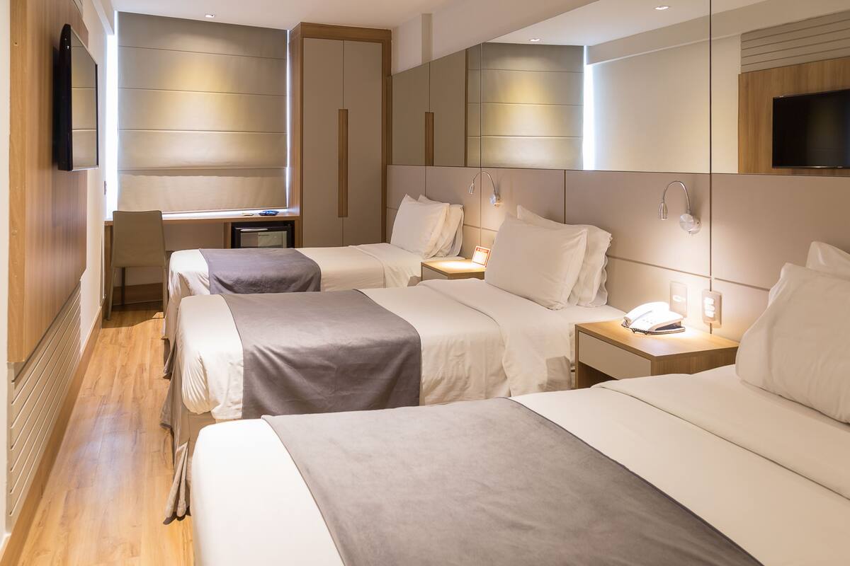 Una habitación de hotel con dos camas, un escritorio, un televisor y un baño.