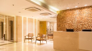 Un área de recepción moderna con una pared texturizada de madera, un mostrador de recepción y varias sillas de mimbre.