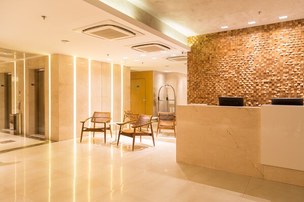 A modern reception area with a wooden textured wall, a reception desk, and several wicker chairs.