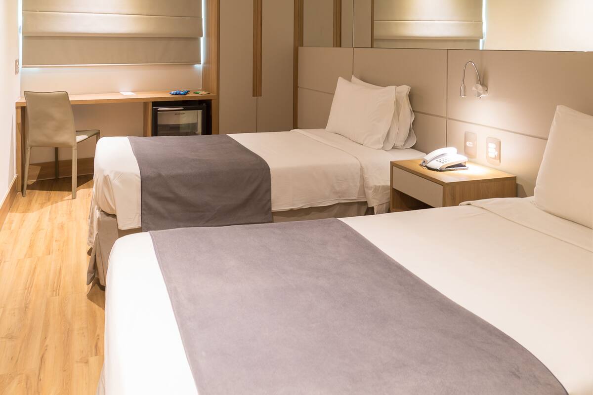 Habitación de hotel con dos camas, un escritorio, una silla y una mesita de noche con teléfono.