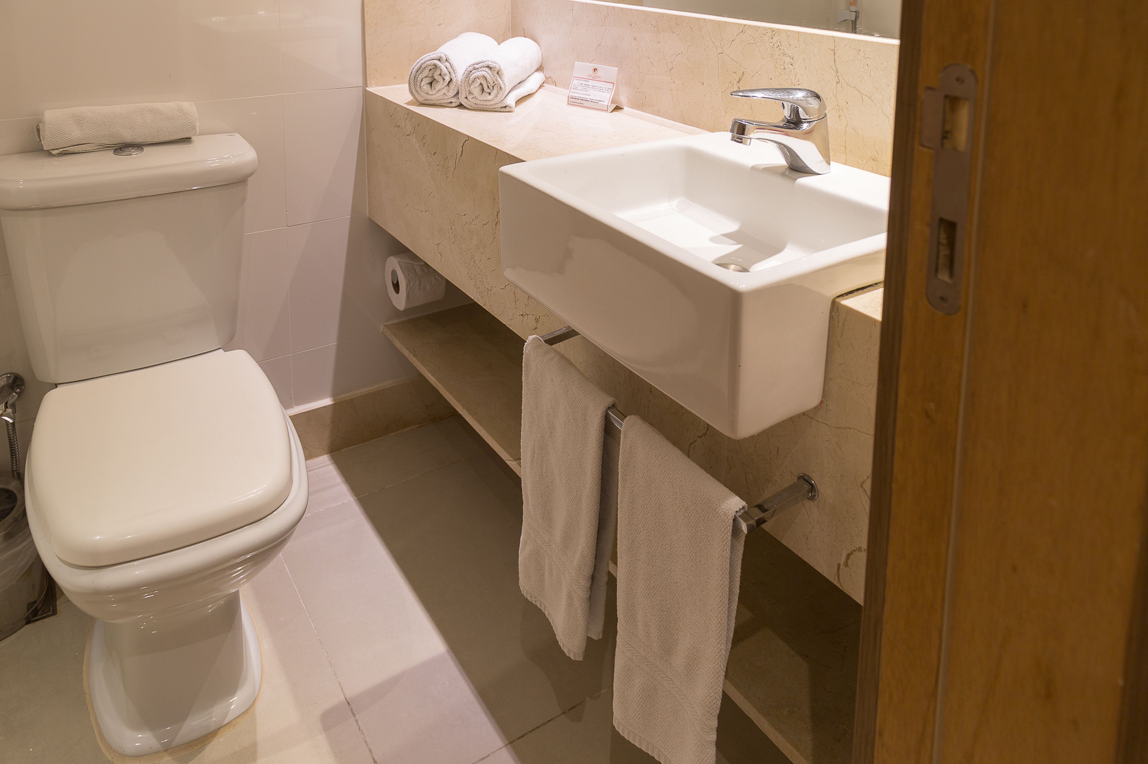 A modern bathroom with a toilet, sink, and towel rack.