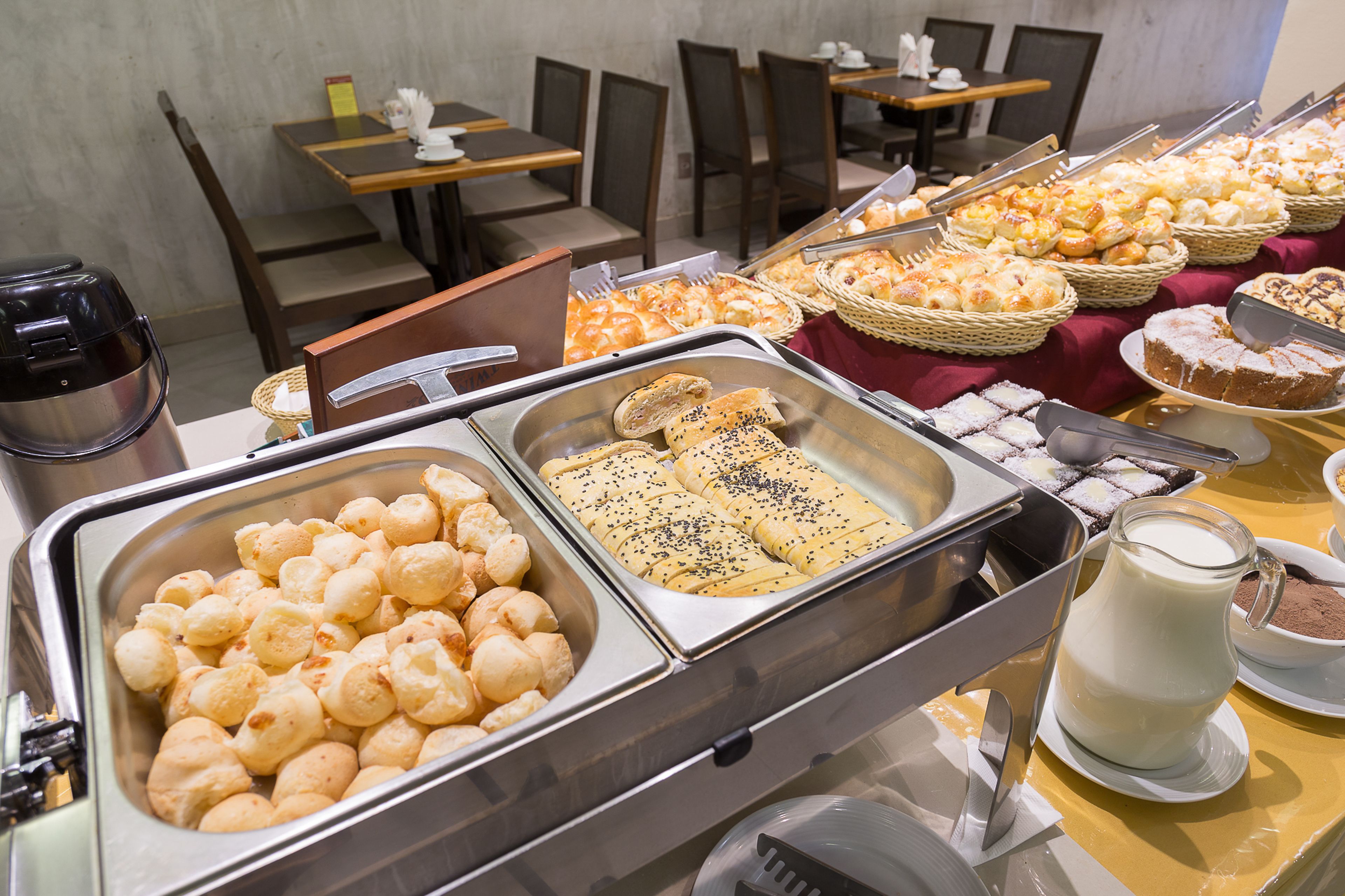 A buffet with various baked goods and a milk pitcher.