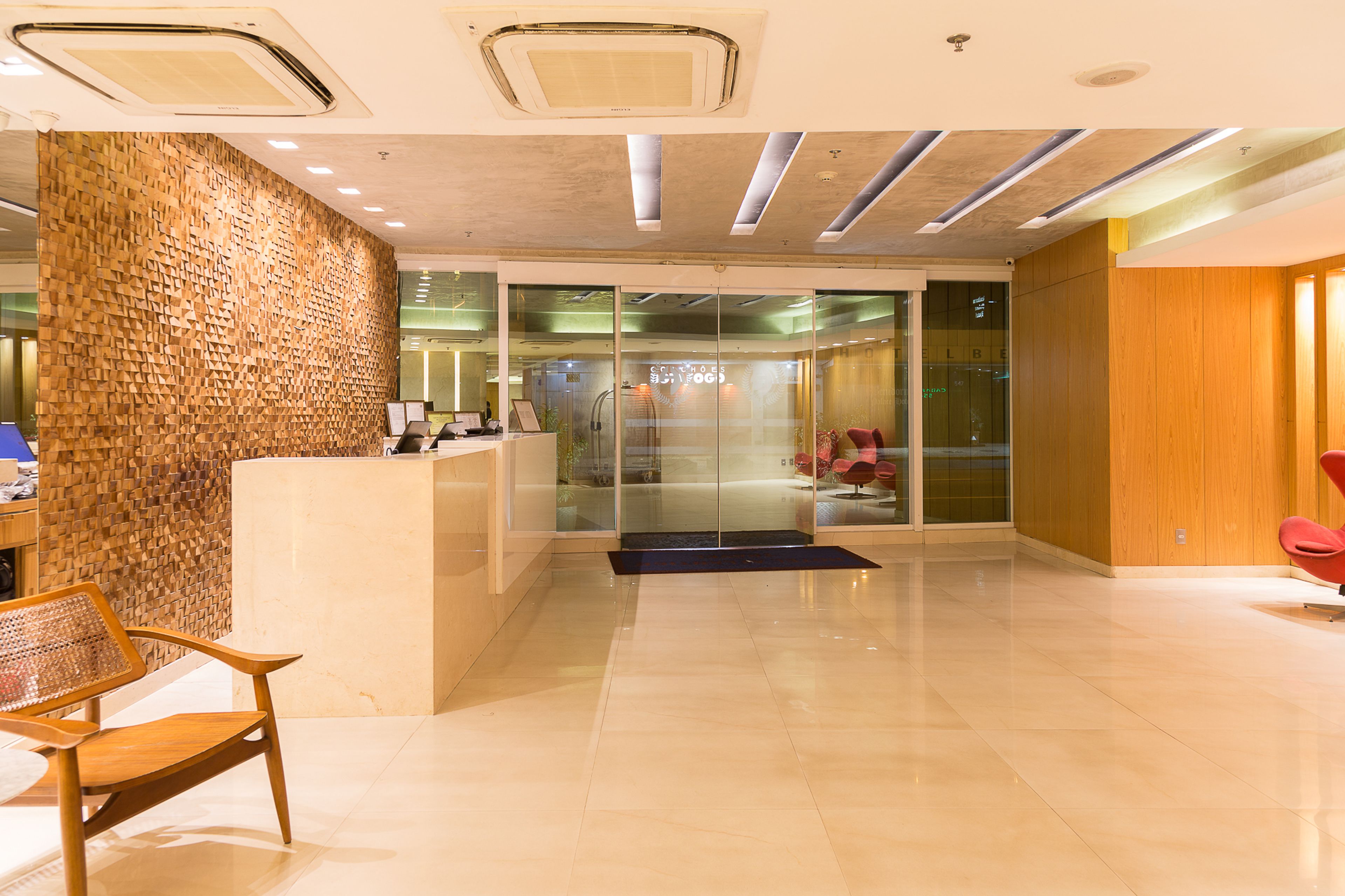 A modern reception area with a wooden wall, a reception desk, and a glass door leading to an interior space.