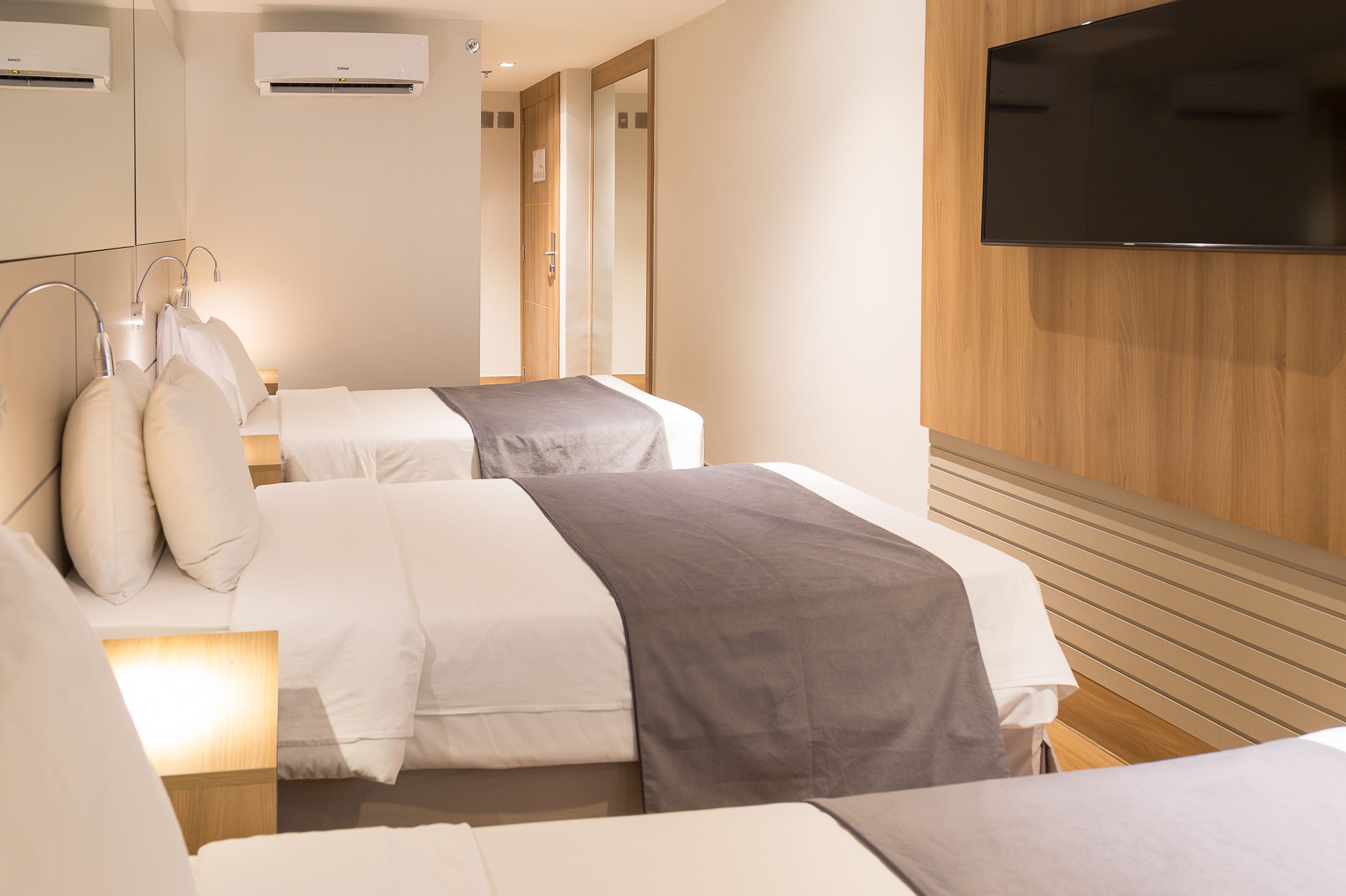 Une chambre d’hôtel avec deux lits, un téléviseur fixé au mur et un décor avec des panneaux en bois.
