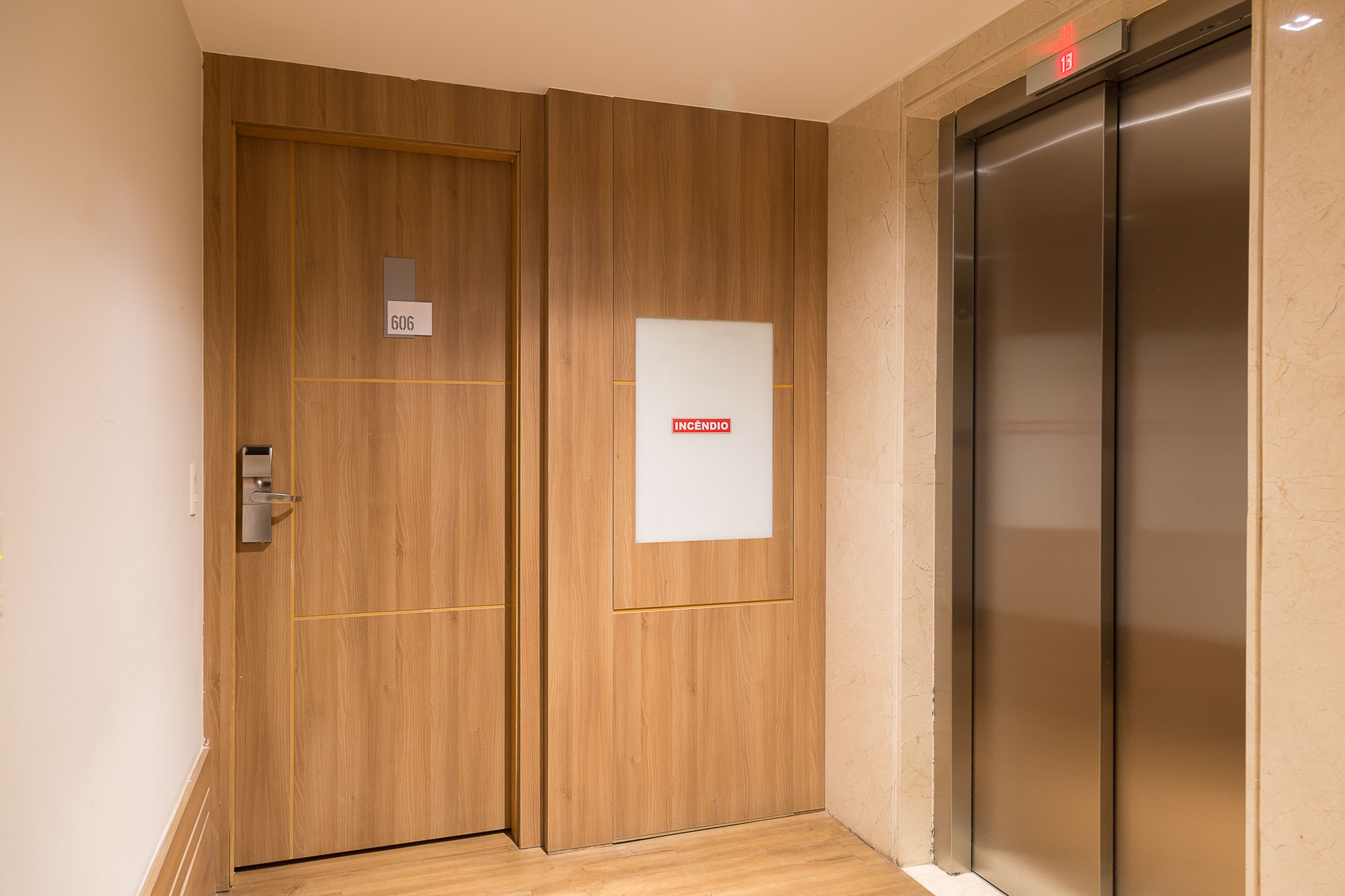 A wooden double door with a digital display and a fire alarm panel.