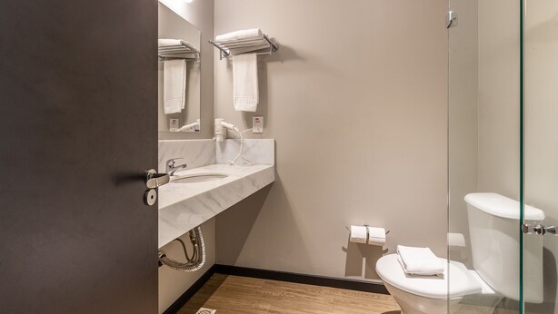 Un baño moderno con lavamanos de mármol, cabina de ducha de vidrio y retrete.