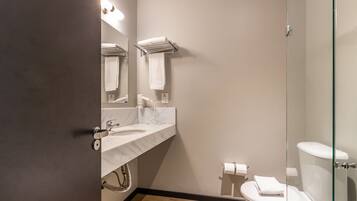 A modern bathroom with a marble sink, a glass shower enclosure, and a toilet.