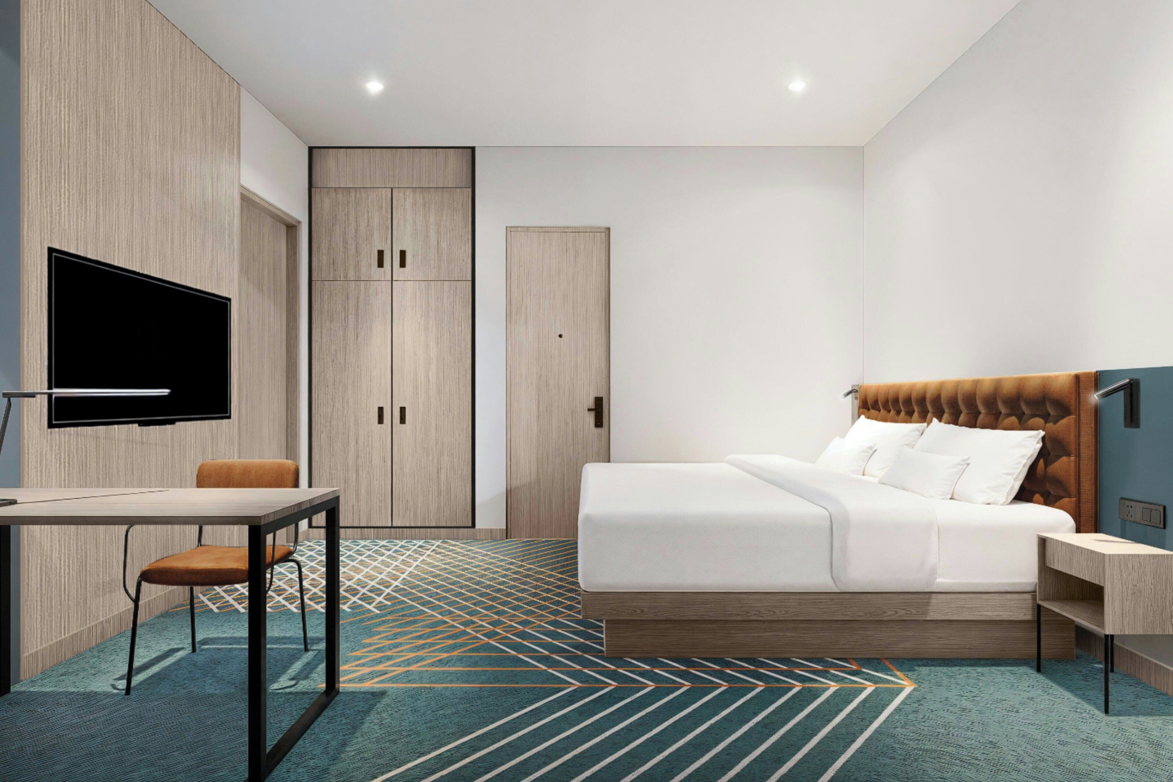 Una habitación de hotel moderna con cama, escritorio, silla, televisor y armarios empotrados.