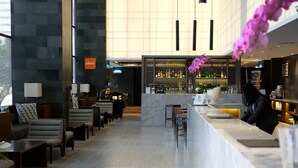 Un moderno vestíbulo de hotel con mostrador de recepción, zona de estar y bar.