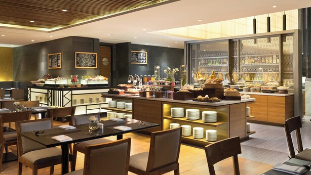 Un restaurante moderno con barra central, mesas de comedor y una mesa de buffet.