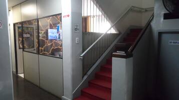 A staircase with red carpeted steps and a metal railing, leading to an upper floor.