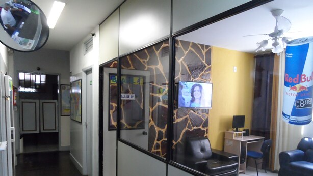 A hotel lobby with a reception desk, a TV screen, and a Red Bull energy drink poster. - Hotel Avenida (Vitoria)