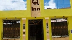 Un hotel con un llamativo letrero 'MOSQ' en la fachada, ventanas amplias y una entrada simétrica con una puerta central.