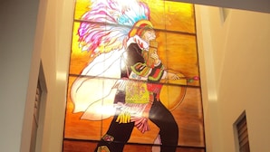 Habitación con un mural grande de una persona tocando un instrumento de cuerda, un sofá y una pequeña mesa.