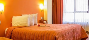A hotel room with a large bed, orange walls, and a window with curtains. - Mosoq Inn (Puno)