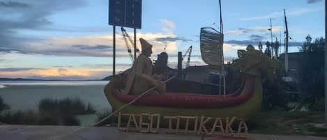 Un modelo de barco con una figura, un cartel con el texto "LAGO TITIKAKA" y una masa de agua al fondo.