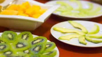 Une table avec des bols remplis de fruits coupés en tranches, notamment des kiwis, des mangues et des avocats.