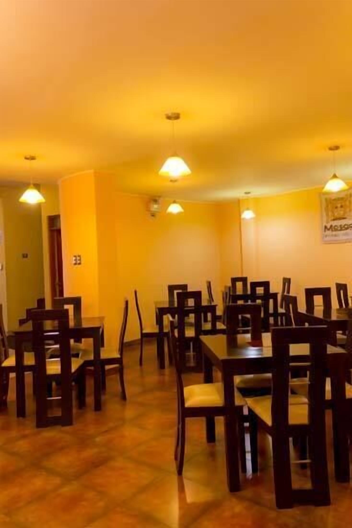 A dining area with multiple tables and chairs, a yellow wall, and ceiling lights.