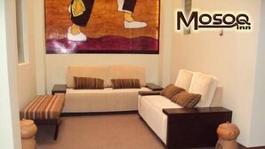 Una sala de estar acogedora con un sofá, dos pufs y una mesa de centro.