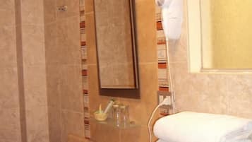 A bathroom with a sink, mirror, towel rack, and a shower area.