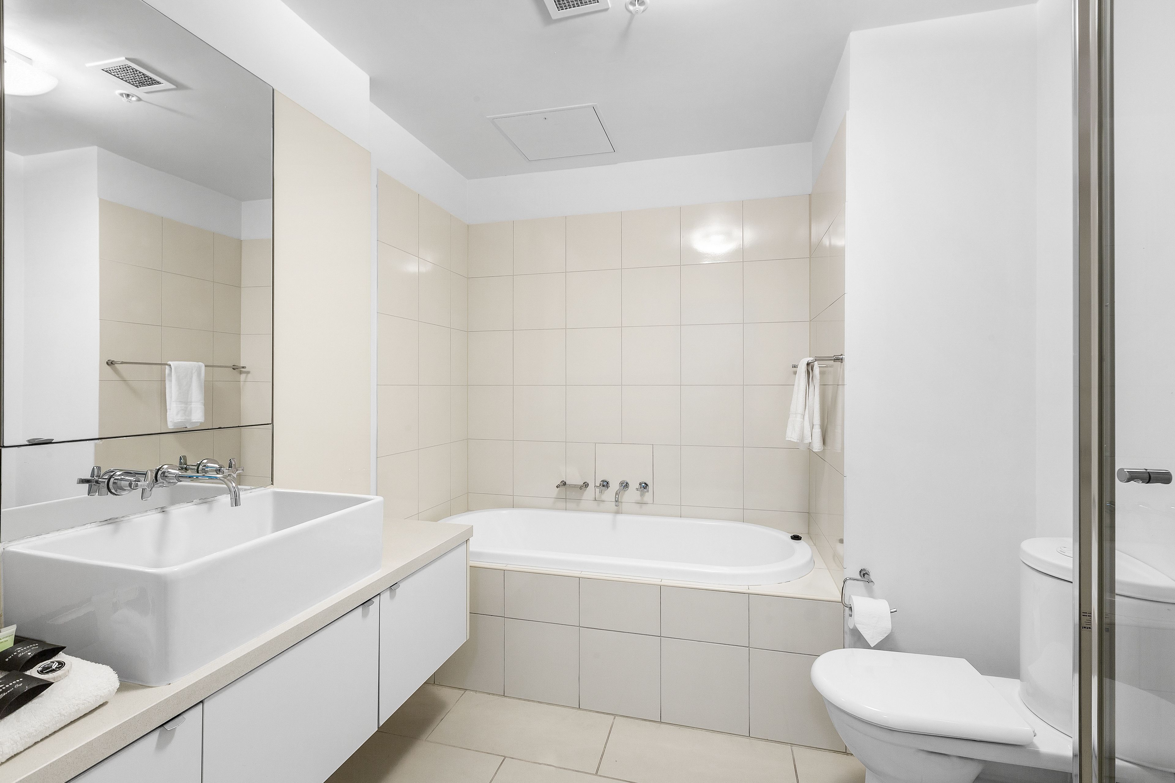A modern bathroom with a large sink, a bathtub, and a toilet.
