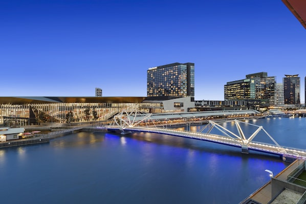 A modern bridge over a calm river, surrounded by high-rise buildings with illuminated windows.