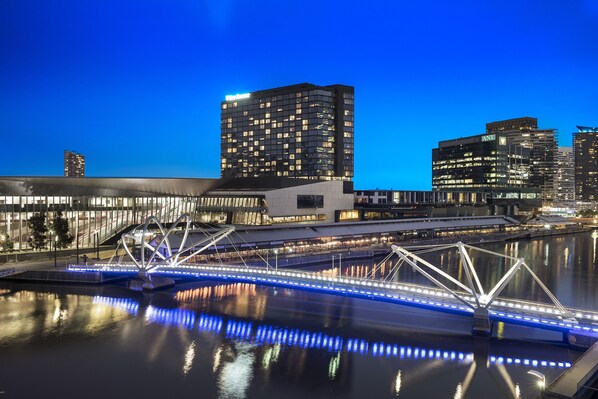 Un pont moderne aux lumières bleues scintillantes qui se reflètent sur l’eau, entouré de gratte-ciel aux fenêtres illuminées.