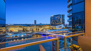 Un hôtel moderne doté d’un balcon en verre donnant sur une zone riveraine, et comprenant une piscine et un pont.