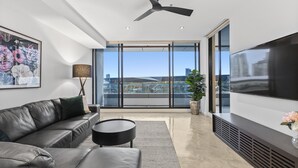 Ein modernes Wohnzimmer mit großem Fernseher, Ledersofa und Deckenventilator.