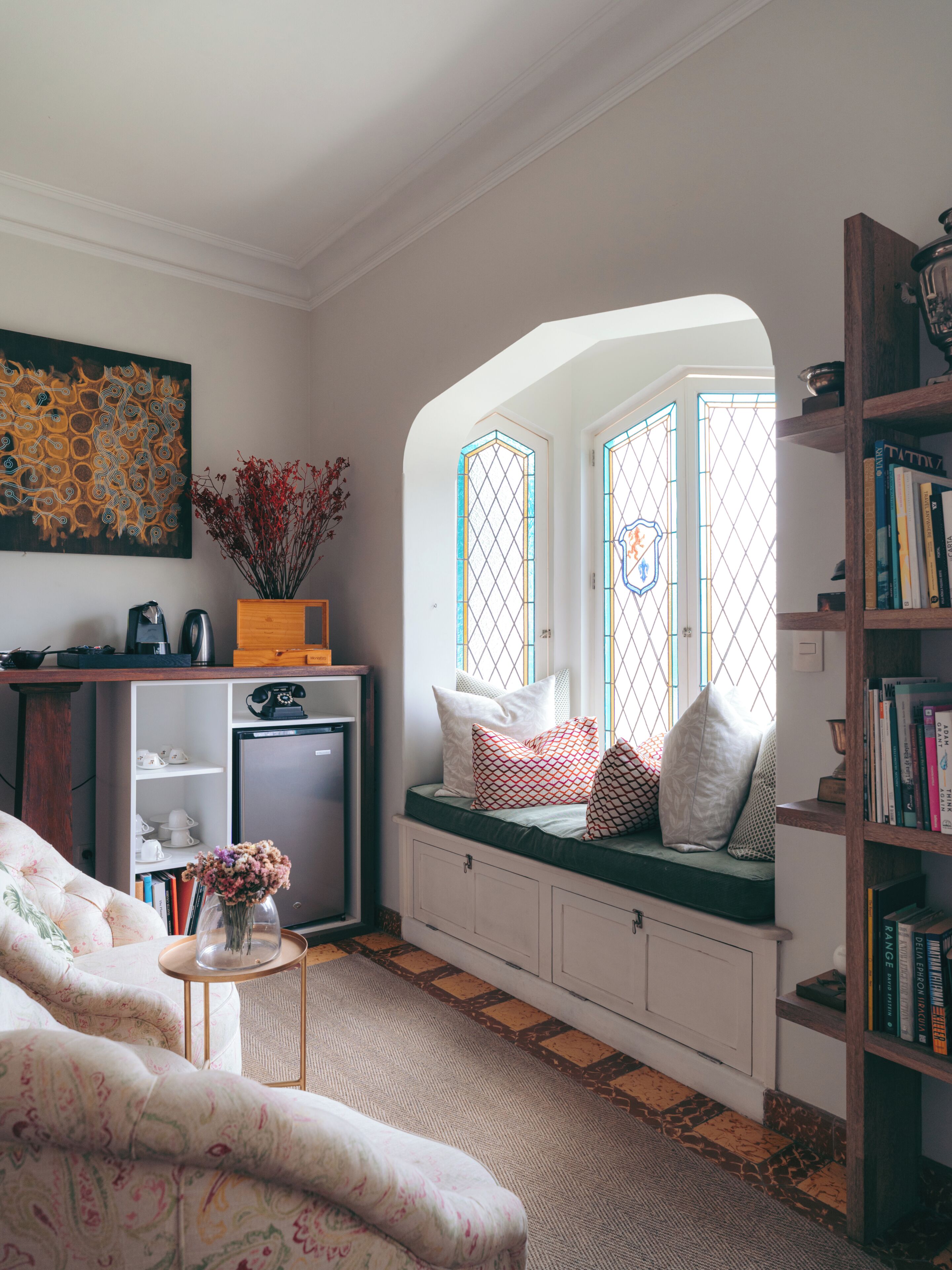 A cozy living room with a built-in bench, a bookshelf, a coffee table, and a decorative painting.