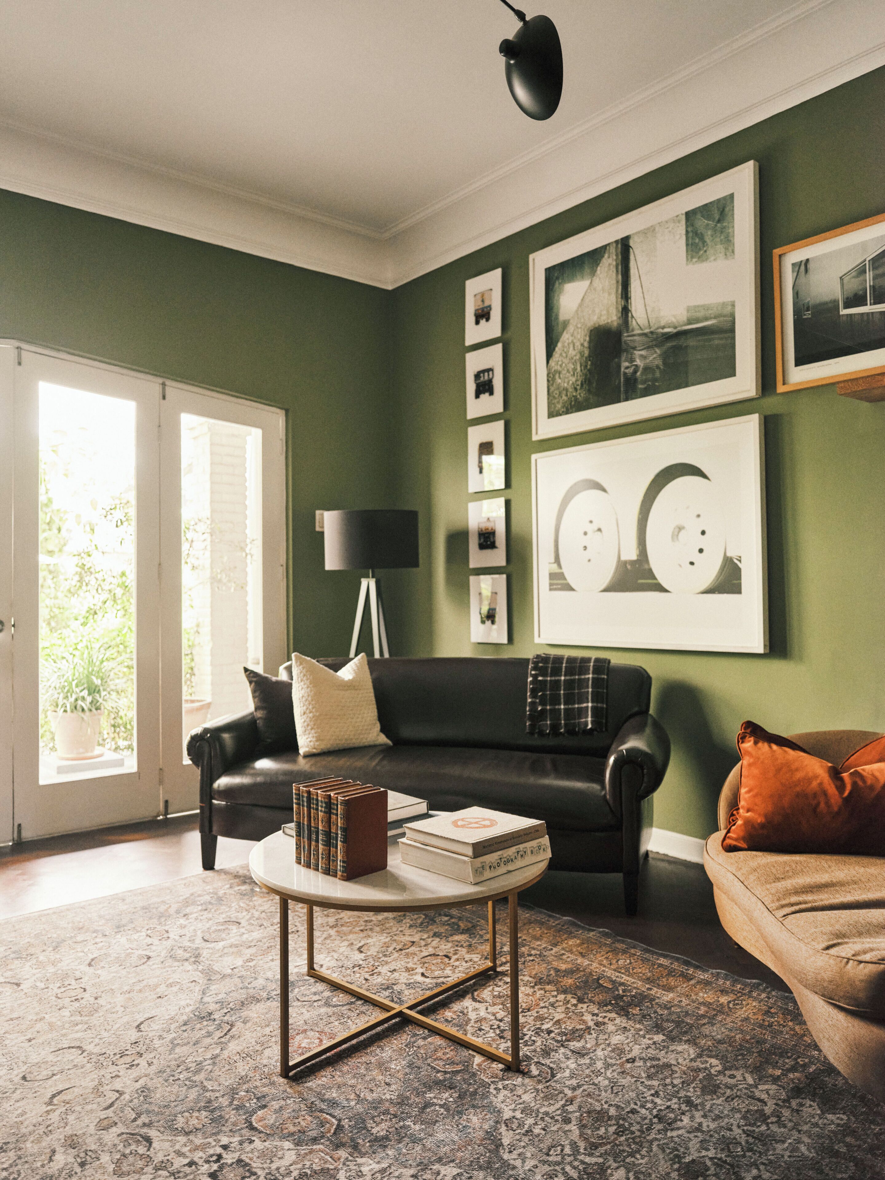 A living room with a sofa, a coffee table, and a lamp. There are framed pictures on the wall.