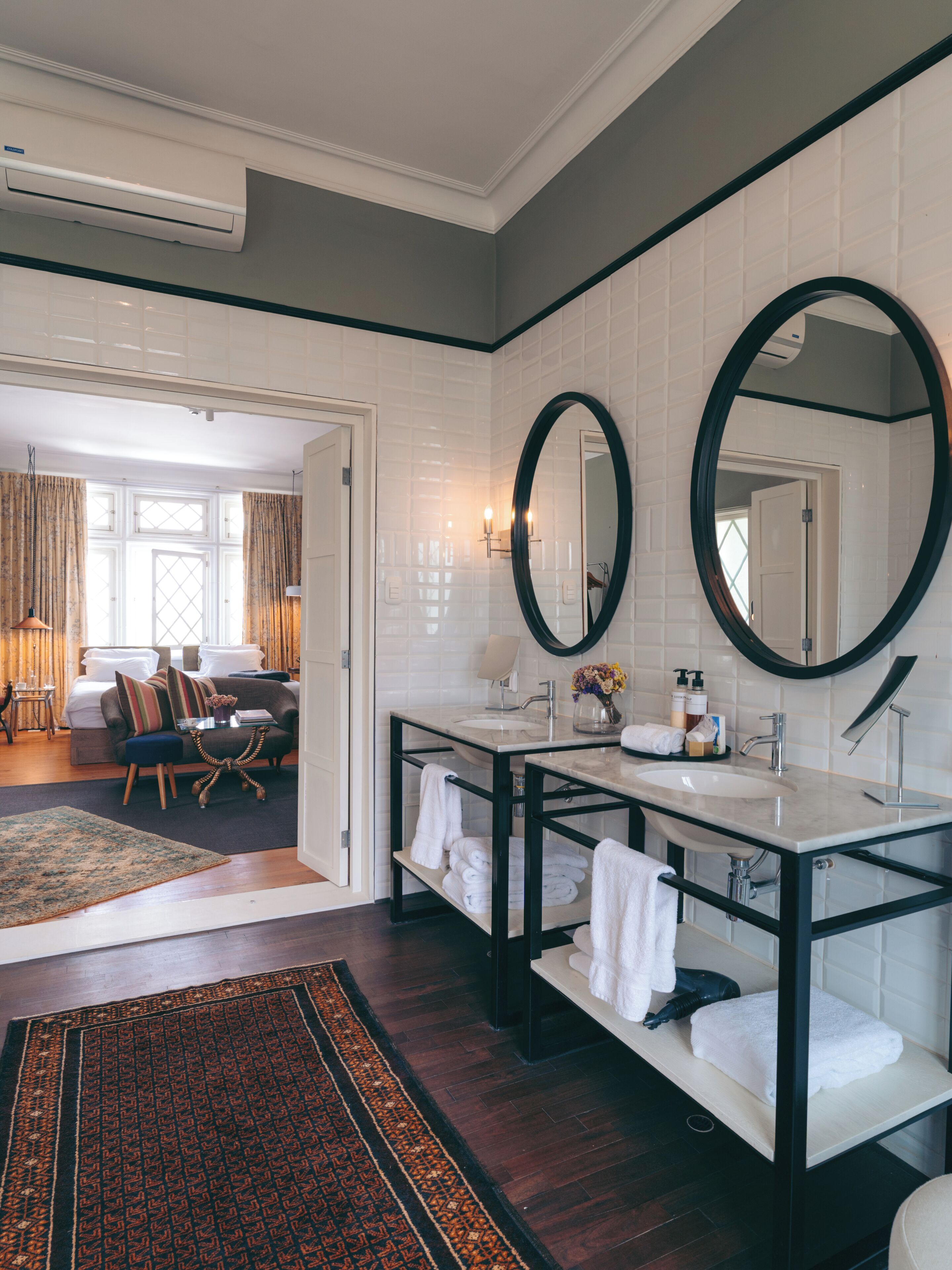 A modern bathroom with two sinks, a large mirror, and a walk-in shower.