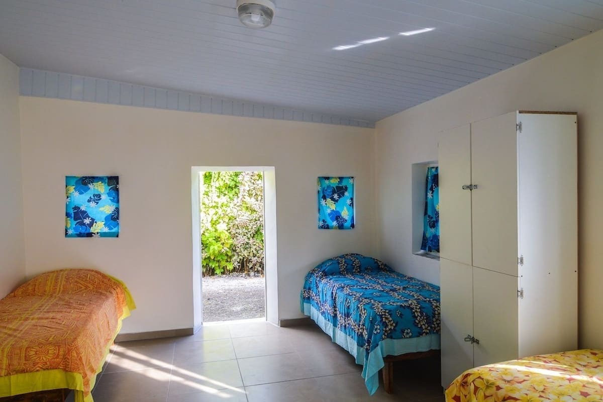 A bedroom with two beds, a wardrobe, and a door leading to a garden.