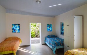 A bedroom with two beds, a wardrobe, and a door leading to a garden.