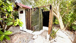 A small white building with a red roof, surrounded by greenery and a gravel path. - Va'a i te Moana (Rangiroa)