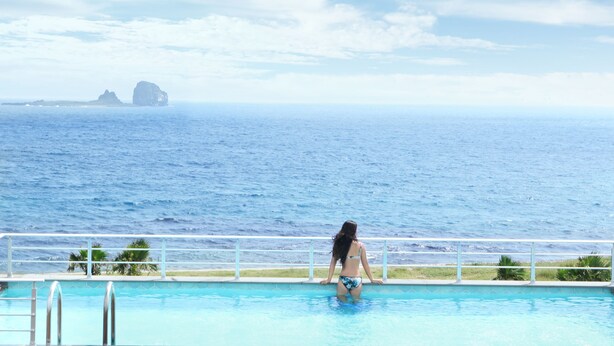 A woman in a bikini at a pool with a view of the ocean and distant islands. - Sun & Moon Resort (Seogwipo)