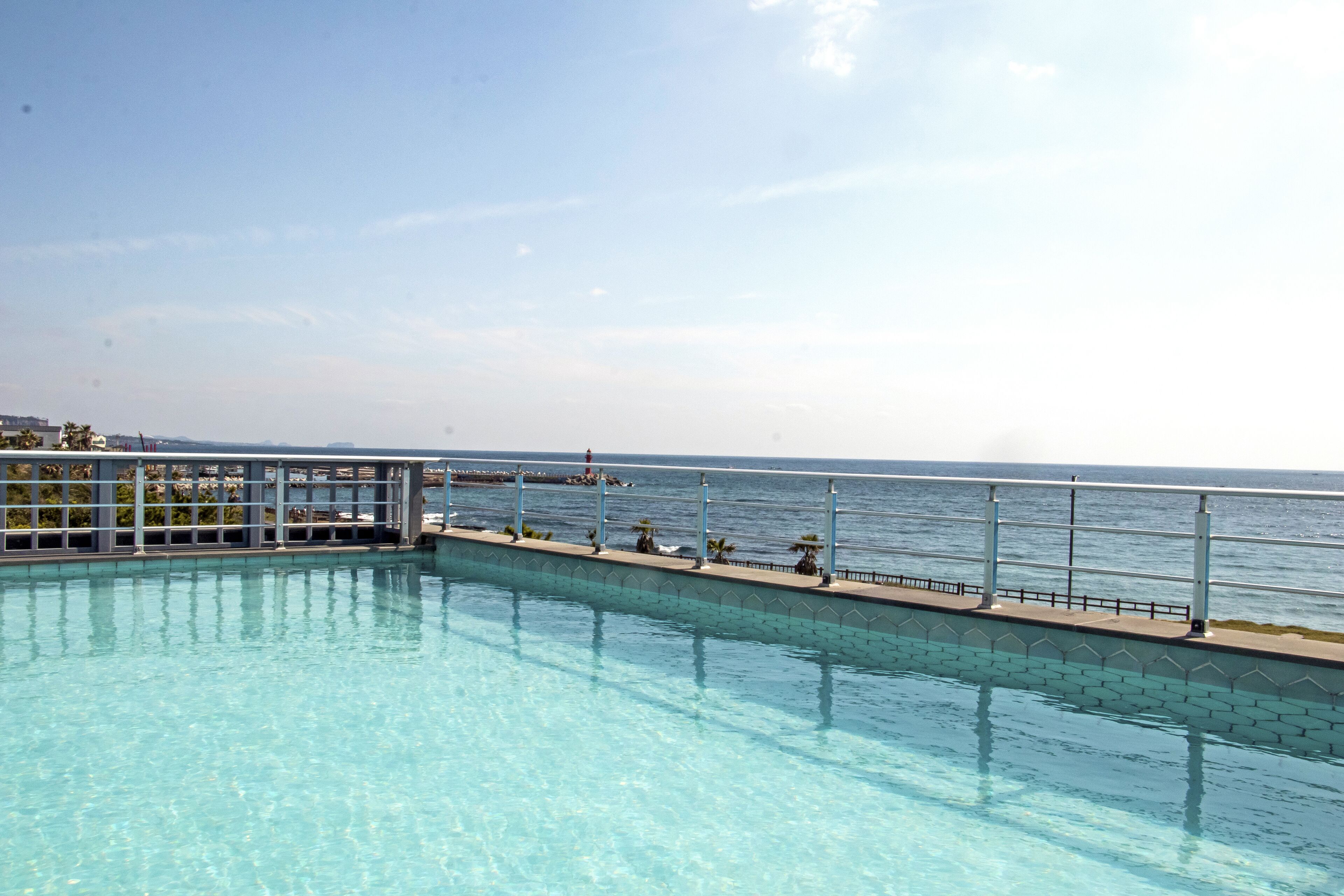 Una piscina azul cristalina con vista al océano y una costa lejana.