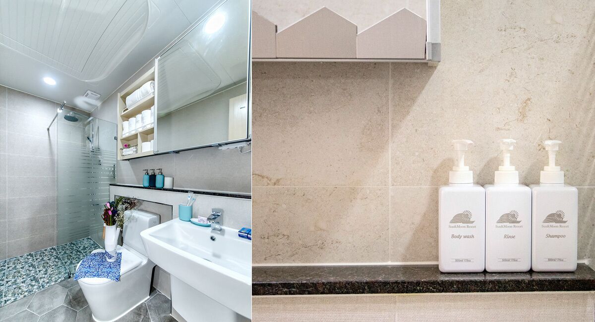 A bathroom with a glass shower enclosure, a white sink, and a vanity with a mirror. There are three bottles of South Moon Resort body wash, rinse, and shampoo on the counter.