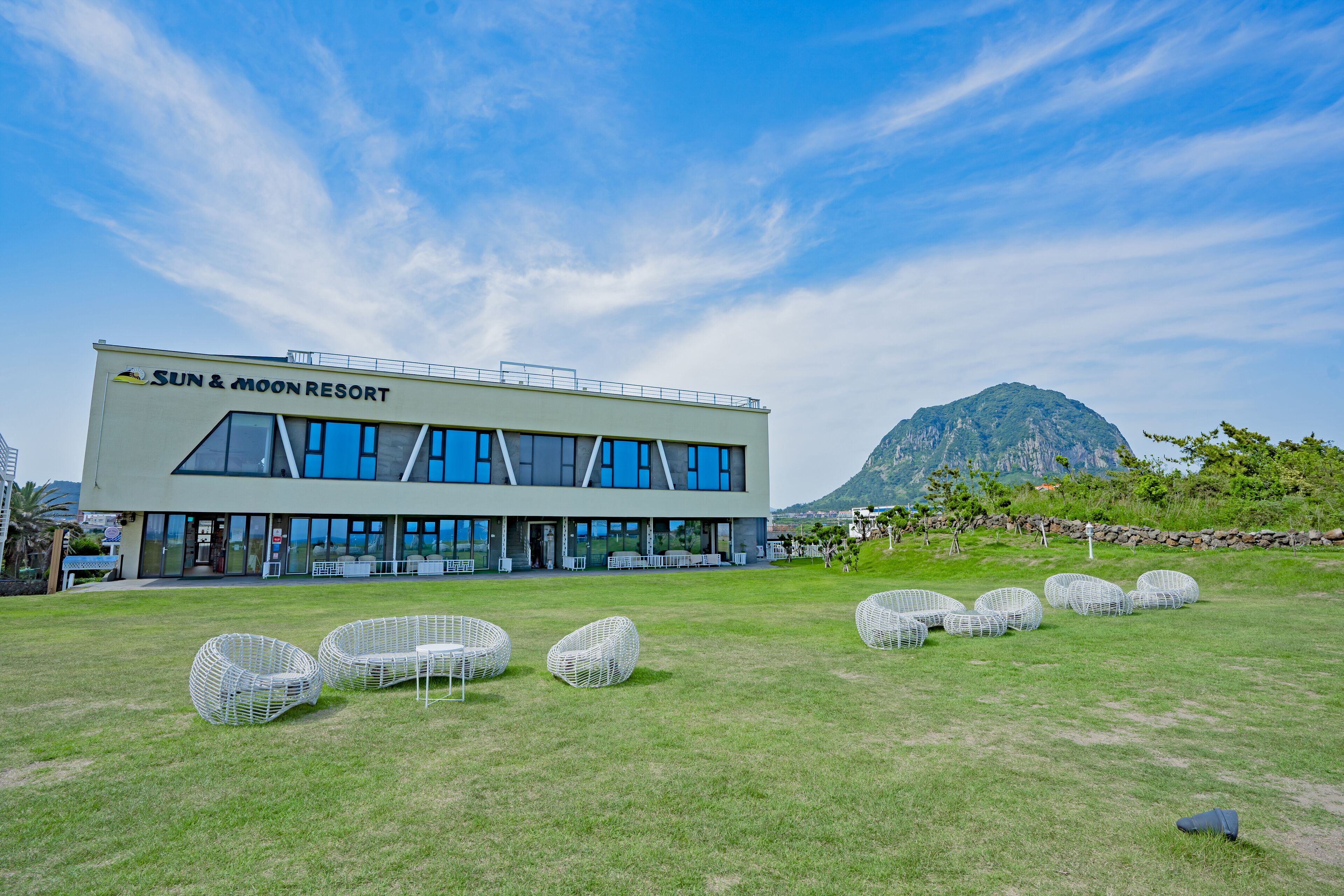 A modern building labeled "Sun & Moon Resort" with a grassy lawn and outdoor seating.