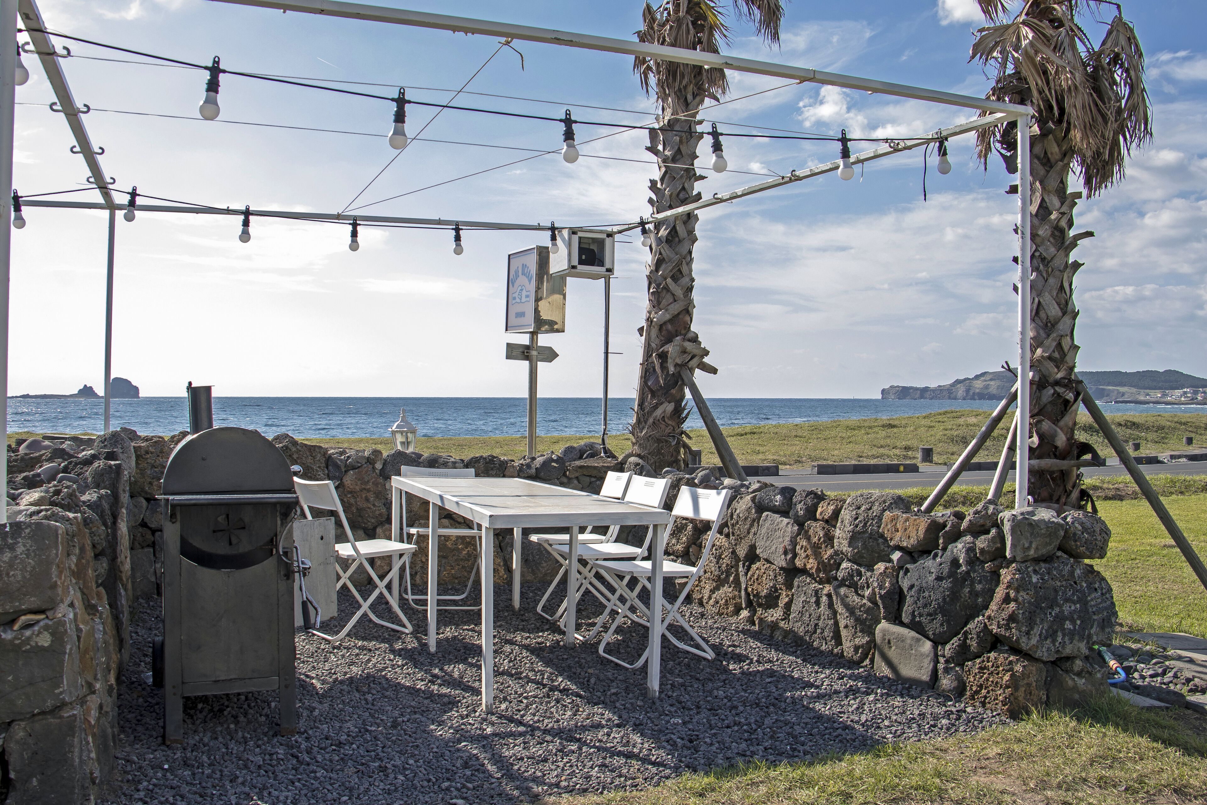 An outdoor seating area with a table and chairs, a grill, and string lights.